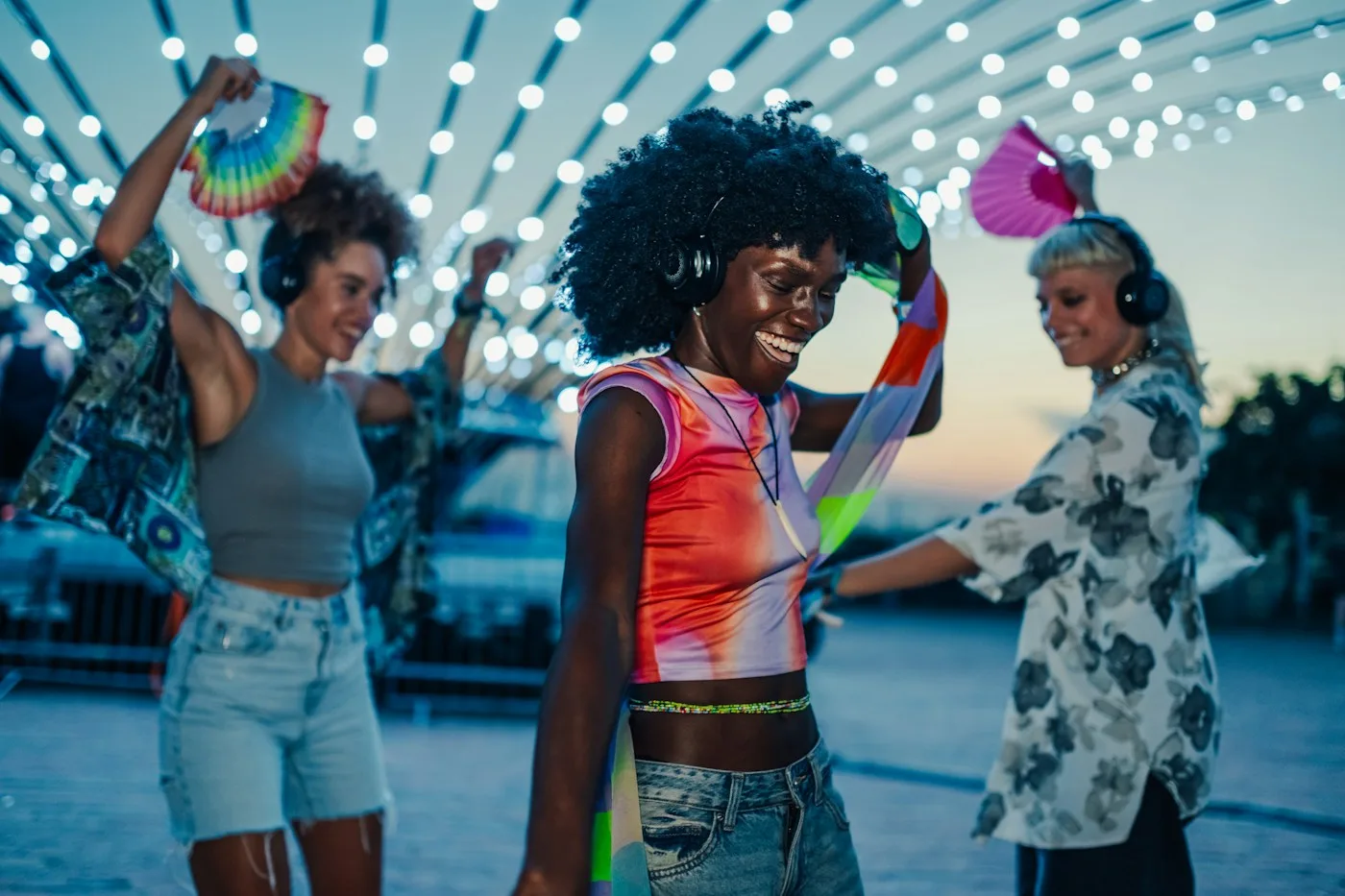 Friends laughing and dancing together at an outdoor silent disco